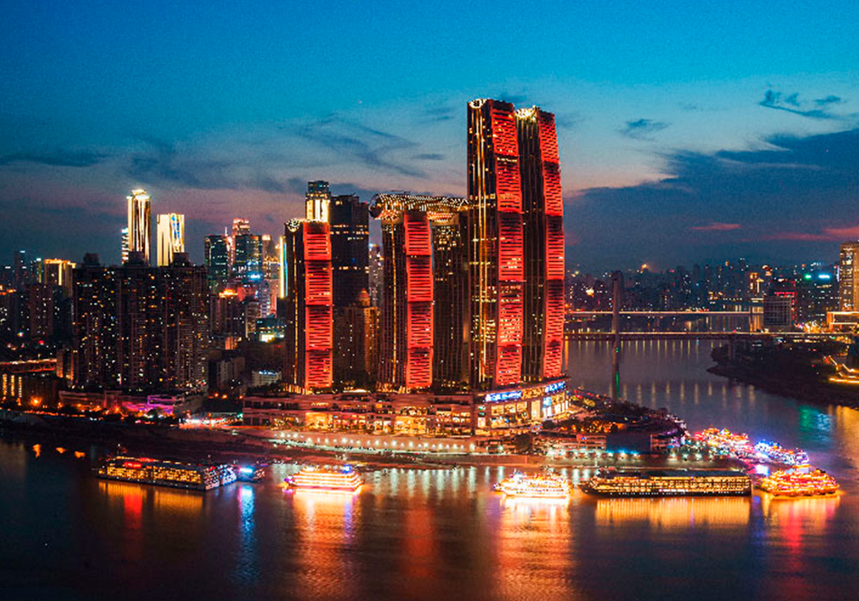 Espectacular skyline nocturno de la ciudad de Chongqing en China, con rascacielos iluminados y barcos turísticos reflejados en el río.